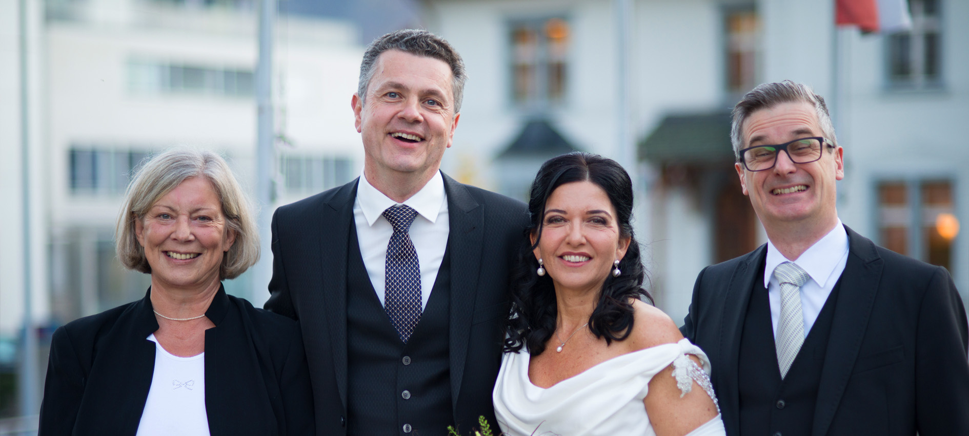 The bride and groom in the center with their two attendants on the outsides in front of the registry office.