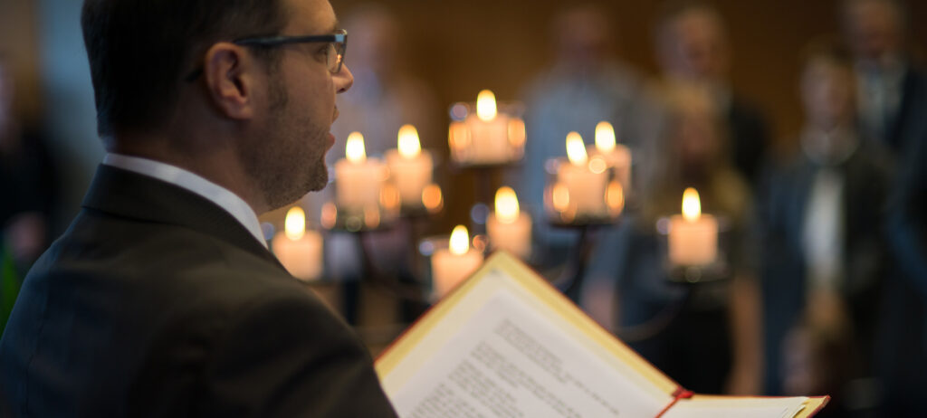 The registrar reads from the folder he holds in his hands. In the background you can see golden flickering candles immersed in blur.