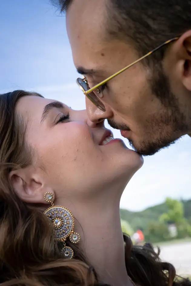 The groom bends down to the bride and kisses her tenderly with closed eyes.